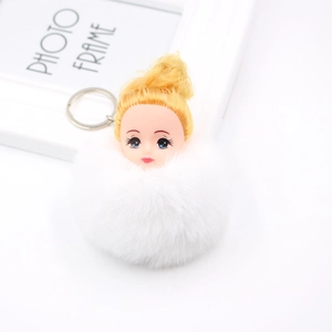 Détail d'un porte-clés poupée endormie avec grand pompon en fourrure blanche et cheveux dorés