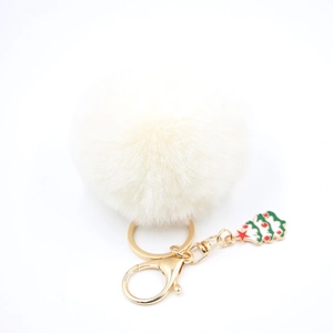 Détail d'un porte-clés pompon blanc en fausse fourrure avec breloque sapin de Noël