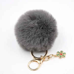 Détail du porte-clés pompon gris en fausse fourrure avec fermoir doré et flocon vert