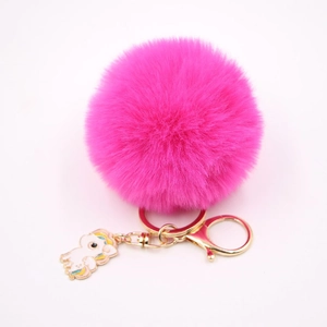 Détail du porte-clés pompon rose vif avec attache dorée et breloque licorne en émail
