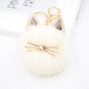 Close-up of white plush cat keychain with golden ears and heart nose detail