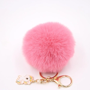 Détail d'un pompon en peluche rose avec fermoir doré et pendentif licorne élégant
