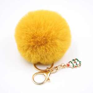 Détail du porte-clés pompon jaune avec breloque sapin de Noël et fermoir en métal doré
