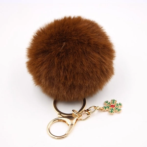 Détail du porte-clés pompon marron café avec fermoir doré et pendentif flocon de neige vert