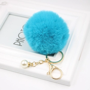 Detail of lake blue faux fur pompom keychain with gold lobster clasp and white pearl bead