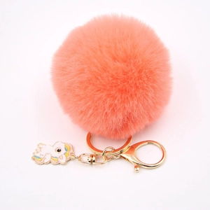 Détail d'un porte-clés pompon rose avec fermoir doré et pendentif licorne