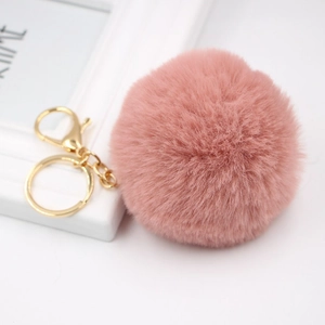 Detailed macro view of soft pink faux rabbit fur pom-pom with golden metal clasp