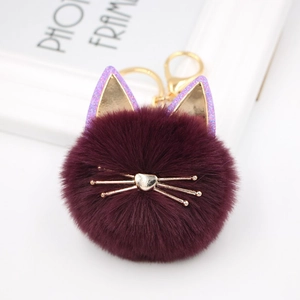 Close-up of fluffy dark purple cat keychain with gold metal ears and whiskers detail