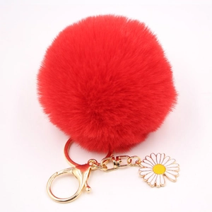 Détails d'un porte-clés pompon rouge en fausse fourrure avec breloque marguerite