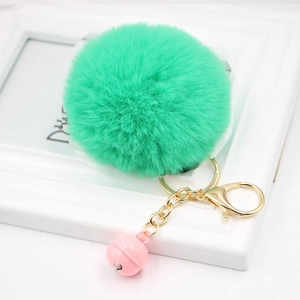 Detailed close-up of fluffy green faux rabbit fur keychain with pink bell and golden clasp