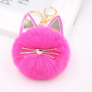 Detailed macro shot of a fluffy pink cat pompom keychain with golden metal whiskers