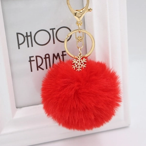 Detail of red plush pom-pom keychain with golden snowflake charm and lobster clasp