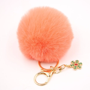 Détail d'un porte-clés pompon en fausse fourrure rose avec fermoir doré et flocon de neige