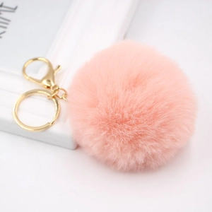 Close-up of fluffy peach faux fur keychain with golden lobster clasp on white background
