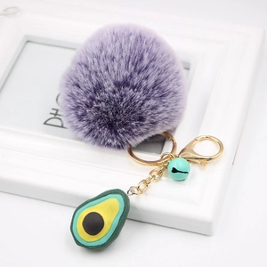 Detail of purple faux fur pompom keychain with golden clip and avocado charm