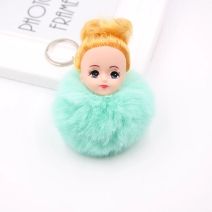 Détail d'un porte-clés pompon en fausse fourrure vert menthe avec tête de poupée