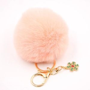 Détail du porte-clés pompon en fourrure rose avec pendentif flocon de neige doré