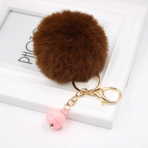 Close-up of fluffy dark brown faux rabbit fur keychain with pink bell and golden metal ring