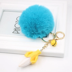 Detail of creative blue faux fur pom-pom keychain with banana charm and golden metal hook