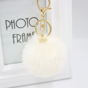 Close-up of cream faux fur keychain with golden alloy snowflake pendant and lobster clasp