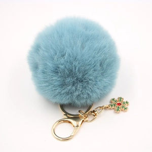 Détail d'un porte-clés pompon bleu clair en fausse fourrure avec flocon de neige doré