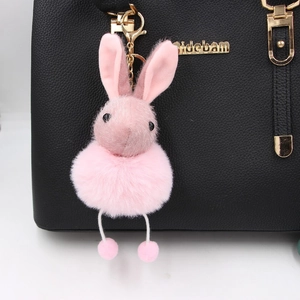 Pink plush bunny ear pendant charm with glitter accents on a black leather bag