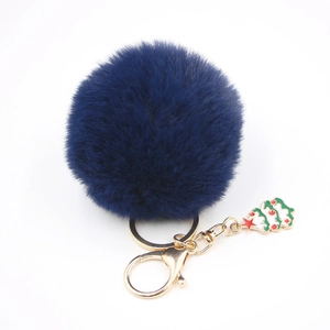 Détail d'un porte-clés pompon bleu marine en fausse fourrure avec breloque sapin de Noël dorée
