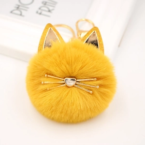 Close-up of yellow plush cat keychain with golden sequins ears and metal whiskers