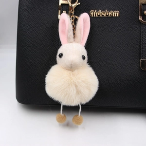 Plush bunny charm with glitter ears and gold clasp on a luxury black leather bag