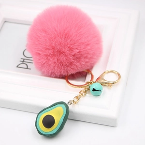 Detail of pink fluffy pompom keychain with golden clasp and avocado charm