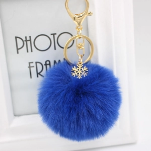 Detail view of a fluffy deep blue plush pompom keychain with golden snowflake charm