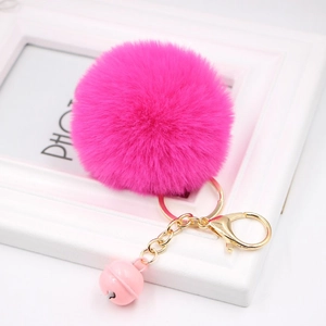 Macro detail of rose red faux fur pompom keychain with golden clip and pink bell