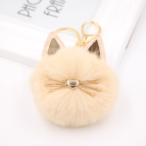 Detail view of a cute plush cat keychain with golden heart nose and metal whiskers