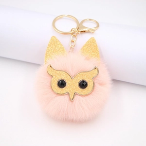 Detailopname van roze faux fur uil sleutelhanger met gouden glitter en metalen haak