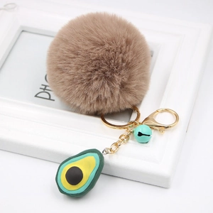 Detail view of avocado plush keychain with brown faux fur ball and golden metal ring