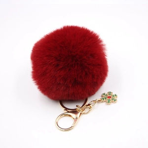 Détail d'un porte-clés pompon en fausse fourrure rouge avec flocon de neige doré