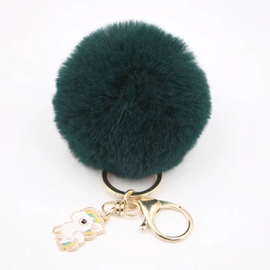 Vue détaillée du porte-clés pompon en fausse fourrure vert foncé avec pendentif licorne doré