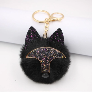 Détail d'un porte-clés renard en peluche noire avec oreilles pailletées et fermoir doré