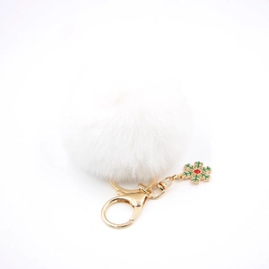 Détail d'un porte-clés pompon blanc avec mousqueton doré et breloque flocon de neige