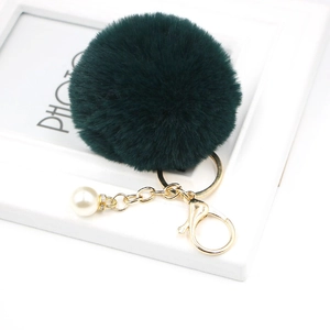 Detailed view of dark green faux fur pompom keychain with gold lobster clasp and white pearl