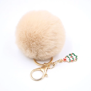 Détail d'un porte-clés pompon en fausse fourrure beige avec fermoir doré et sapin de Noël