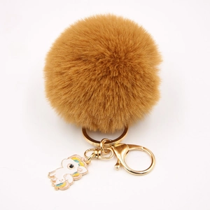 Détail du porte-clés pompon en fausse fourrure camel avec breloque licorne et métal doré
