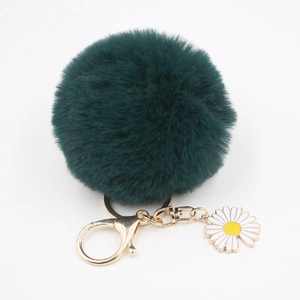 Détail d'un porte-clés pompon en fourrure vert foncé avec fermoir doré et breloque marguerite