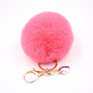 Close-up of pink fluffy pompom keychain with golden clasp and cute unicorn charm