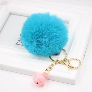 Close-up of sky blue faux fur pompom keychain with golden metal chain and pink bell