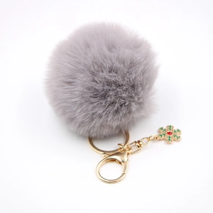 Détail d'un porte-clés pompon gris en fausse fourrure avec fermoir doré et flocon de neige