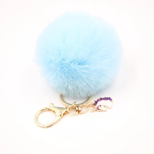 Detail of light blue faux fur pompom keychain with golden lobster clasp and unicorn charm