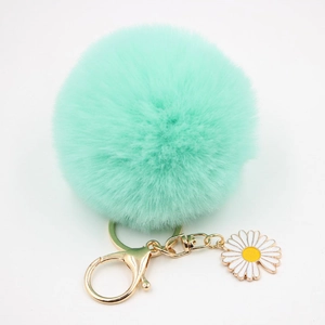 Gros plan sur porte-clés pompon vert menthe avec marguerite et fermoir doré