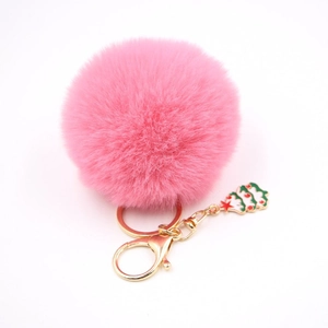 Détail du porte-clés pompon en fausse fourrure rose avec breloque sapin de Noël en émail