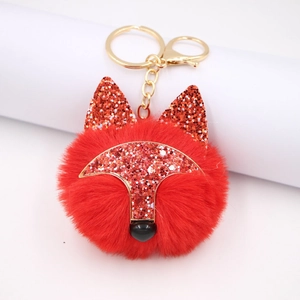Détail d'un porte-clés renard en peluche rouge avec oreilles pailletées et fermoir doré